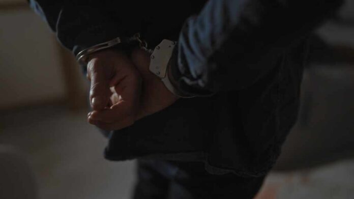 A,Handcuffed,Man's,Hands,Close-up,In,A,Dimly,Lit,Indoor