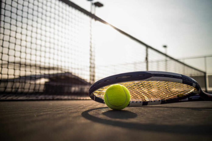Tennis,Ball,And,Racket,On,Hard,Court,Under,Sunlight