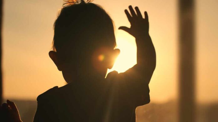 Backlit,Silhouette,Of,A,Baby,Raising,A,Hand,Towards,The