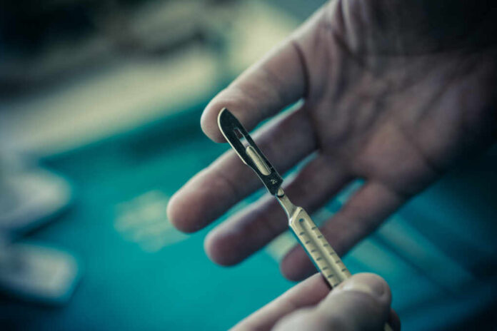 The,Hands,Of,A,Surgeon,Using,A,Metal,Scalpel
