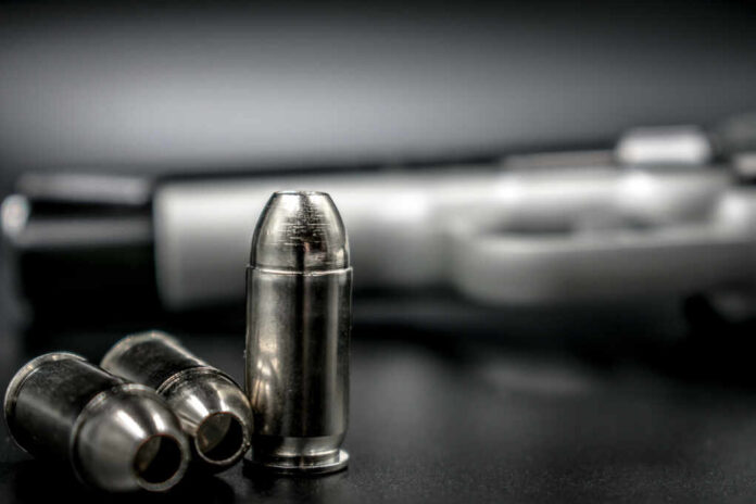 Silver,Hollow,Point,Bullets,With,Gun,In,The,Background