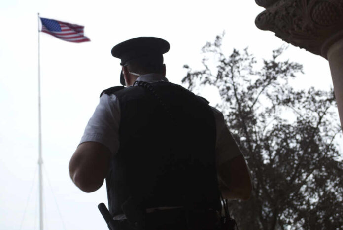 Police,Officer,/,Guard,In,Front,Of,American,Flag