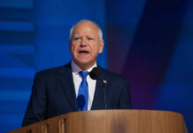 A man in a suit speaking at a podium with a microphone