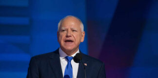 A man in a suit speaking at a podium with a microphone