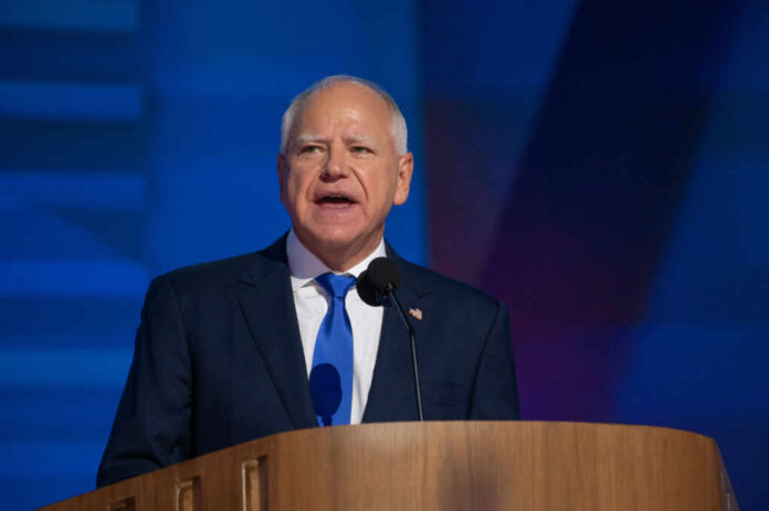 A man in a suit speaking at a podium with a microphone