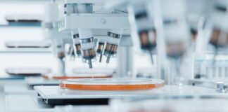 Automated laboratory equipment with robotic arms dispensing liquids into petri dishes
