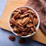 Bowl of pecans on a wooden cutting board