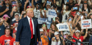 Donald Trump at a political rally with supporters holding signs