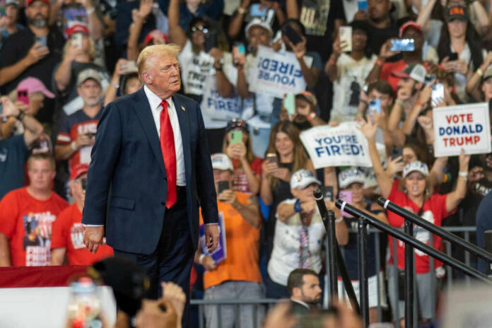 Donald Trump at a political rally with supporters holding signs