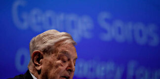 Elderly man speaking at a conference with a blue background