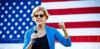 A woman speaking passionately into a microphone in front of an American flag