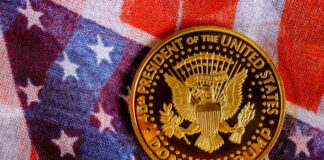 A commemorative coin featuring the presidential seal and the name Donald Trump on an American flag background