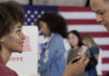 A woman presenting her ID to a man at a voting station