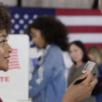 A woman presenting her ID to a man at a voting station