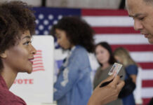 A woman presenting her ID to a man at a voting station