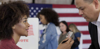 A woman presenting her ID to a man at a voting station