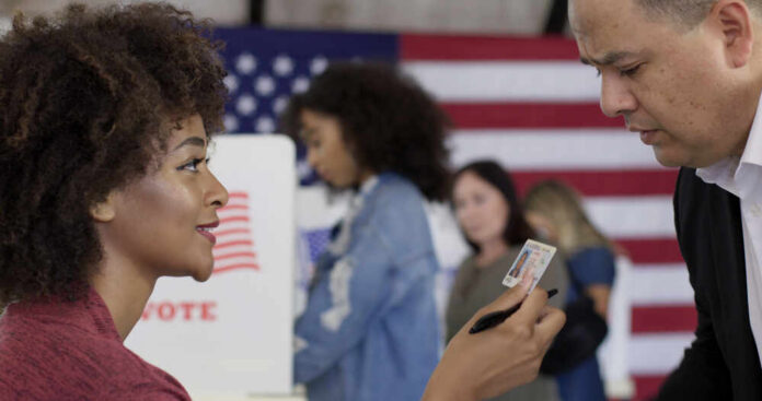 A woman presenting her ID to a man at a voting station