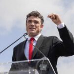 A man in a suit speaking passionately at a podium during an outdoor event
