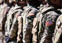 Line of soldiers in military uniforms with American flag patches