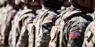 Line of soldiers in military uniforms with American flag patches