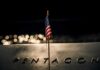 Pentagon’s Press Crackdown DEEMED Unconstitutional A small American flag positioned in front of the word 'PENTAGON' on a reflective surface