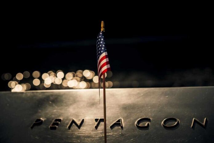 A small American flag positioned in front of the word 'PENTAGON' on a reflective surface