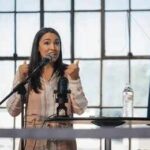A woman speaking passionately at a podium with a microphone