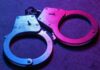 Close-up of metallic handcuffs illuminated with neon lights