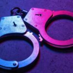 Close-up of metallic handcuffs illuminated with neon lights