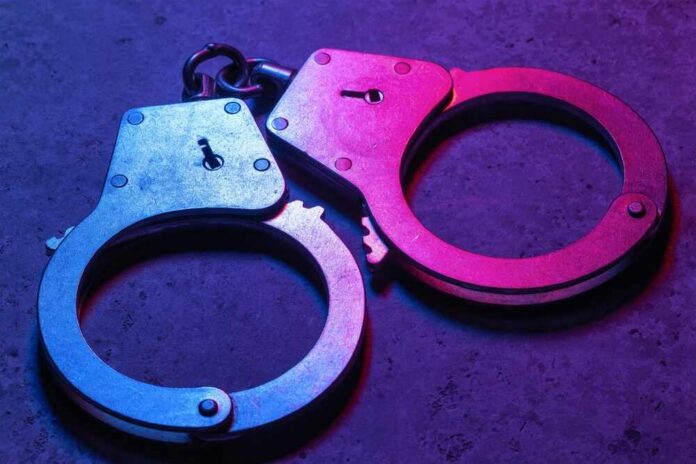 Close-up of metallic handcuffs illuminated with neon lights