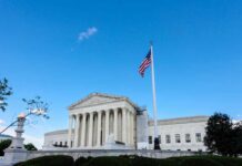 U.S. Supreme Court building with American flag and blue sky
