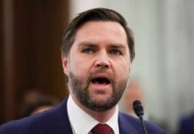 A man in a suit passionately speaking at a podium