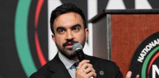 A speaker at a conference holding a microphone and gesturing while speaking