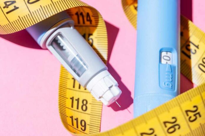 An insulin pen and measuring tape on a pink background