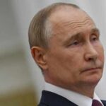 A serious-looking man in formal attire with a neutral expression