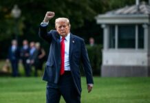 A political figure walking outdoors with a raised fist