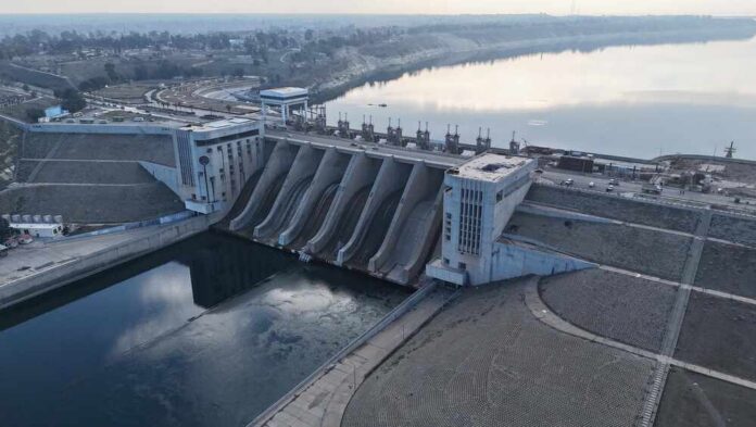 Aerial view of a large dam with water flowing through its gates