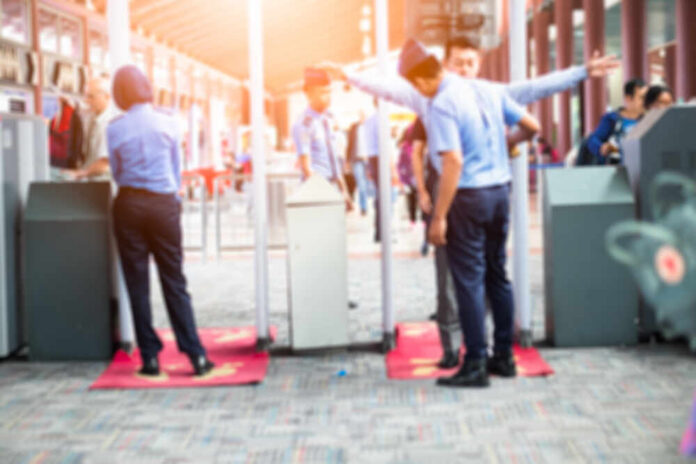 Airport security personnel assisting passengers at a checkpoint