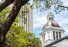 View of a historic government building with a dome and surrounding trees