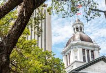 View of a historic government building with a dome and surrounding trees