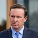 Senator’s “Unpatriotic” Accusations Ignite Firestorm A politician with a serious expression standing outdoors