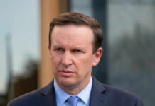 A politician with a serious expression standing outdoors