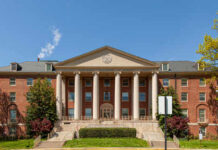 Front view of a historic brick building with columns and landscaped grounds
