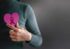 Person holding a pink heart with a ribbon symbol