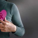 Person holding a pink heart with a ribbon symbol