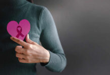 Aggressive Breast Cancer “Switches Off” Immunity Person holding a pink heart with a ribbon symbol