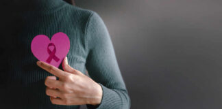 Person holding a pink heart with a ribbon symbol