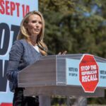 Speaker at a podium addressing a crowd at a political rally