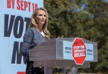 Speaker at a podium addressing a crowd at a political rally