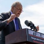 A politician passionately speaking at a podium with a sign advocating for gun safety laws
